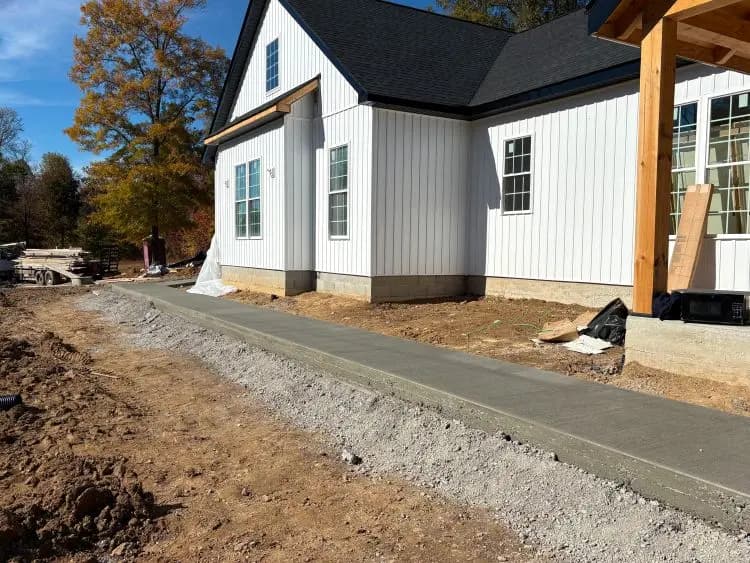 New concrete sidewalk and apron beside a white farmhouse