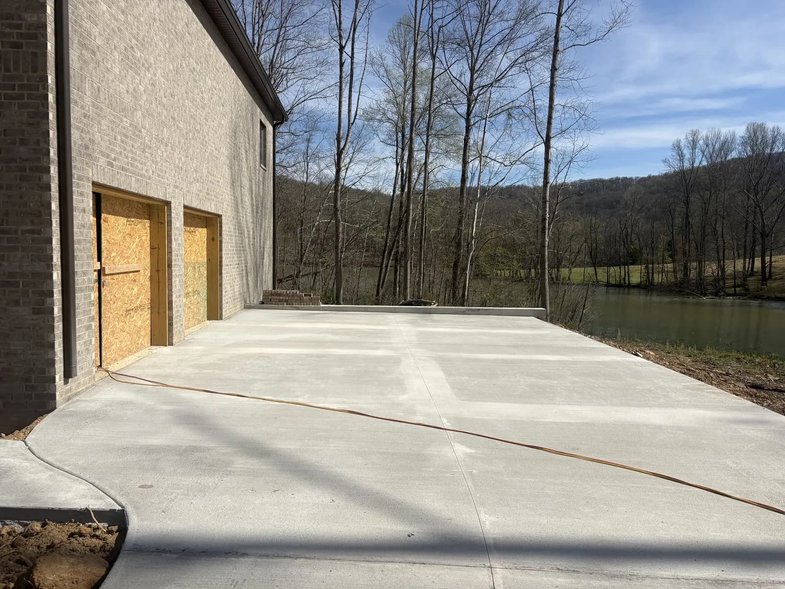Wide concrete garage apron and parking pad beside a brick home
