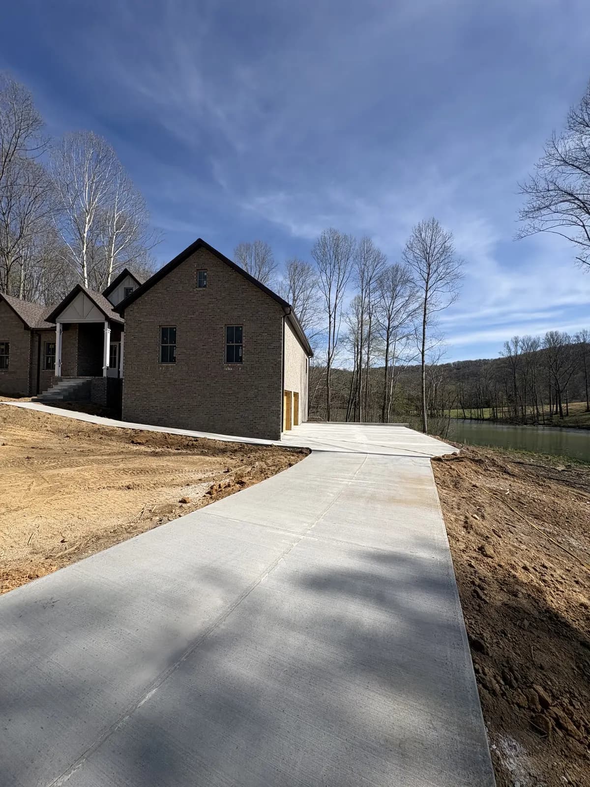 Fresh concrete driveway leading to a new brick home