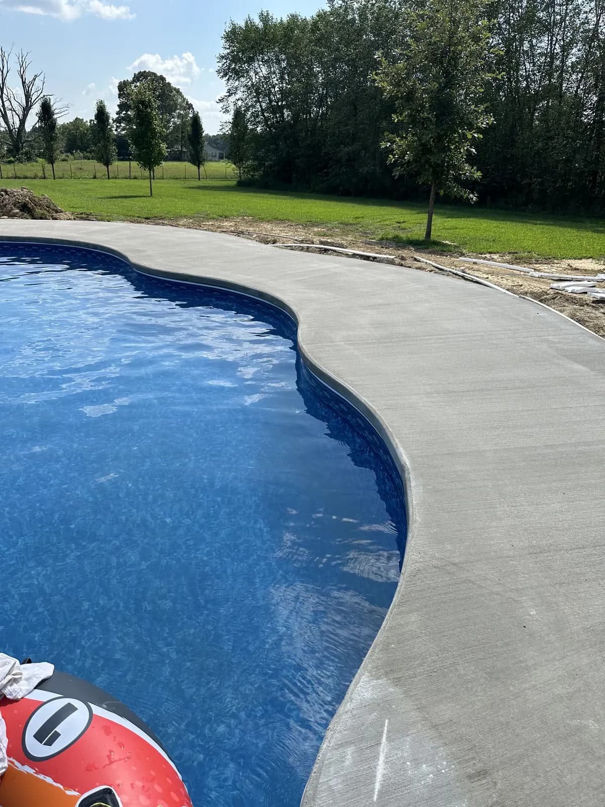 Curved concrete pool deck following the shape of an inground pool