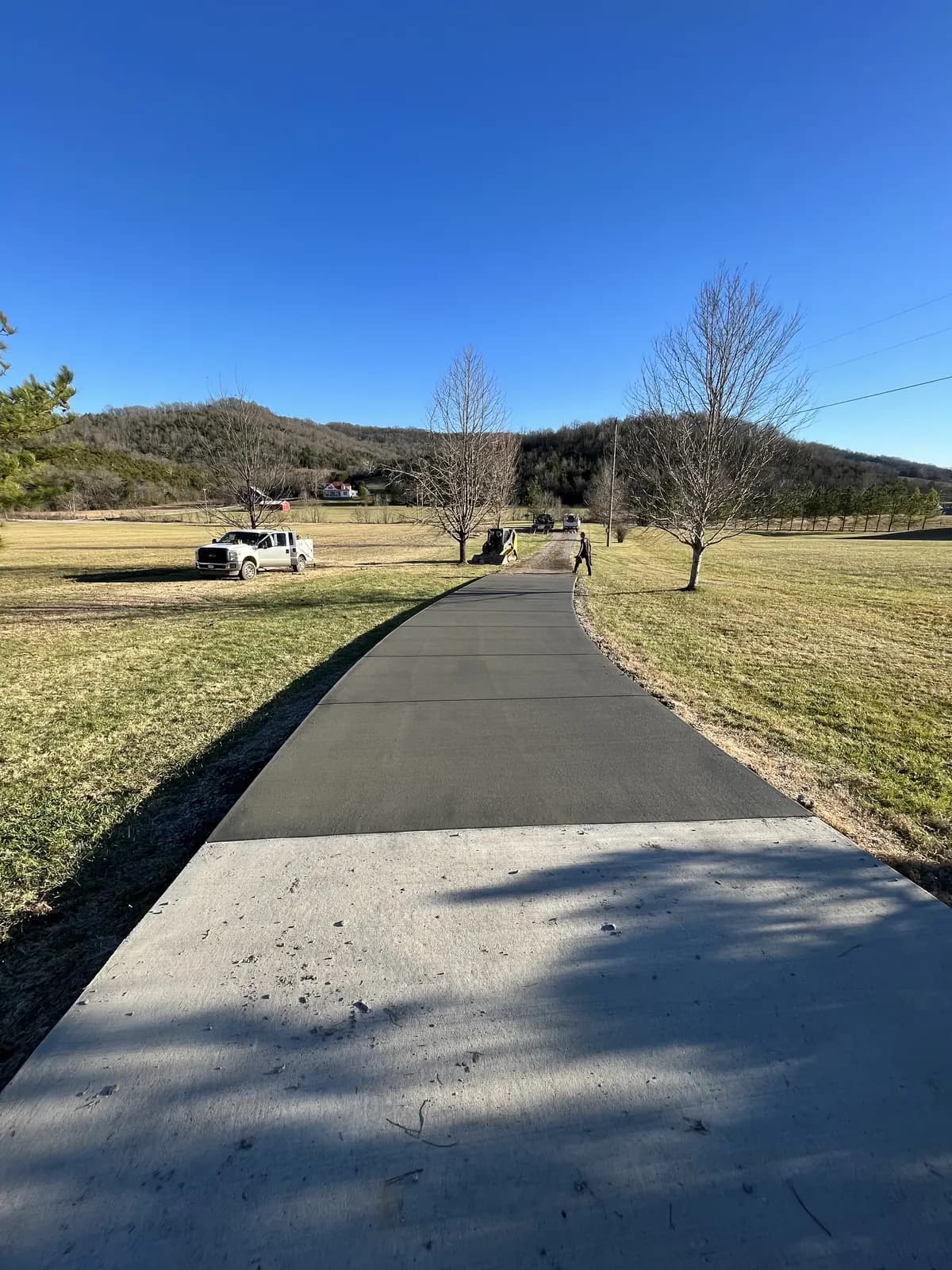 Long new concrete driveway across an open rural property